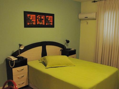 a bedroom with a bed with a yellow bedspread at Hotel Uruguay Brasil in Rivera