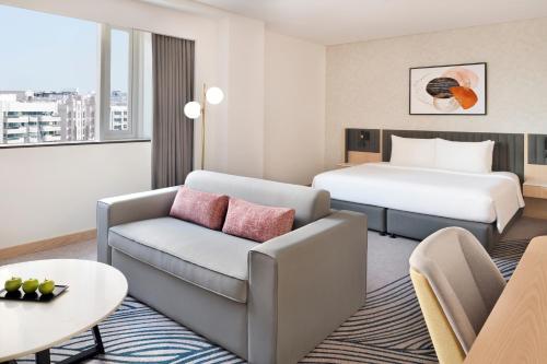 Crowne Plaza - Dubai Jumeirah, an IHG Hotel في دبي: غرفه فندقيه بسرير واريكه