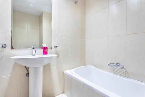a white bathroom with a sink and a bath tub at Live and experience a stunning Sea View Studio in Ras al Khaimah