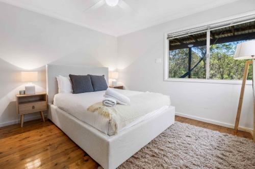 a white bedroom with a bed and a window at Yarramie in Mount View