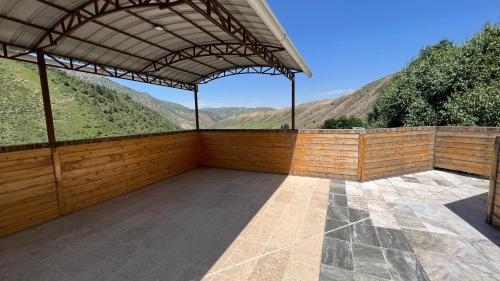 an empty patio with a roof with mountains in the background at Гостевой дом Коль-тор in Kegeti