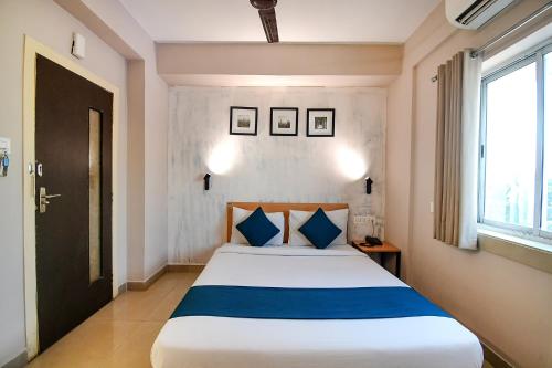 ein Schlafzimmer mit einem großen Bett mit blauen Kissen in der Unterkunft FabHotel Azure Sky Hussainpur in Kalkutta