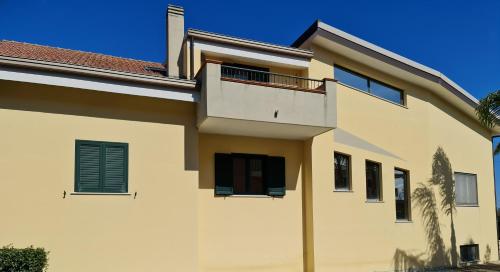 a white house with a balcony on top of it at Villa Toti in Montepaone
