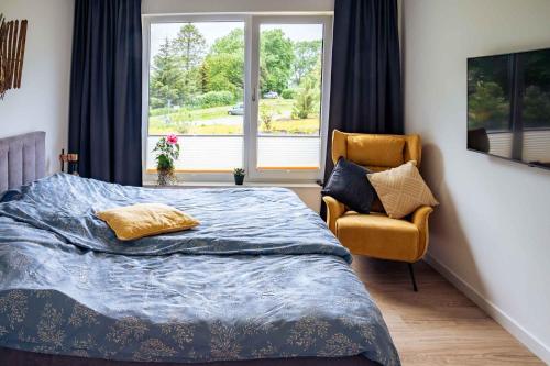 a bedroom with a bed and a chair and a window at Villa am Schloss Ranzow - Baltic Blue in Lohme