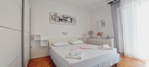 a white bedroom with a bed with two towels on it at APARTMENT ELI in Pag