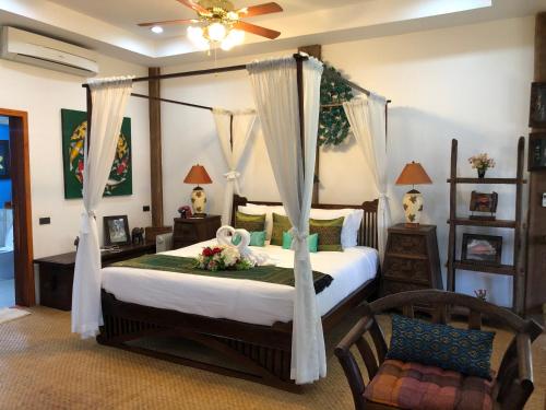 Un dormitorio con una cama con dosel y flores. en On The Mekong Resort, en Luang Prabang