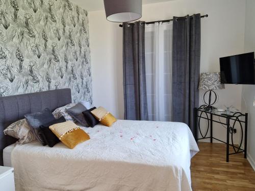 a bedroom with a bed with pillows on it at L'entre deux Eaux 'Maison' Balcon 'et Jardin in Reims