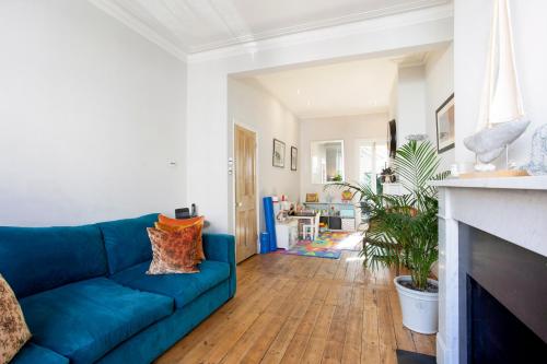 a living room with a blue couch and a fireplace at ALTIDO 3-bedroom family home w/ garden in London