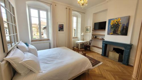ein Schlafzimmer mit einem weißen Bett und einem Kamin in der Unterkunft Chambres d'Hôtes du Marché aux Grains in Bouxwiller