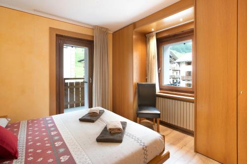 a bedroom with a bed and a chair and a window at Casa Marmut in Livigno