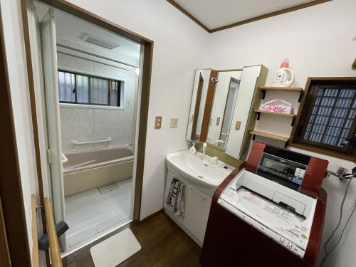 a bathroom with a sink and a tub and a mirror at ゲストハウス　鍼灸院　boshcetto in Yoshino