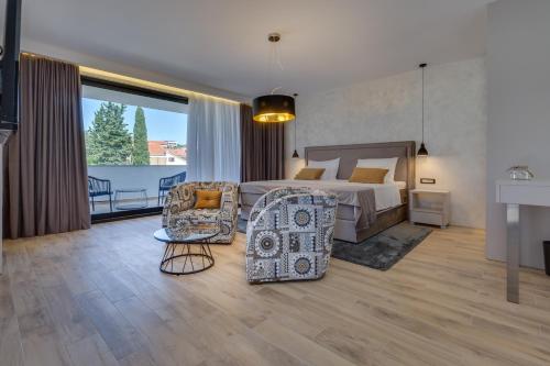 een slaapkamer met een bed, een bank en een stoel bij Mirabilis Residence II in Zadar
