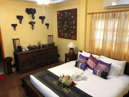 a bedroom with a bed with white sheets and purple pillows at On The Mekong Resort in Luang Prabang