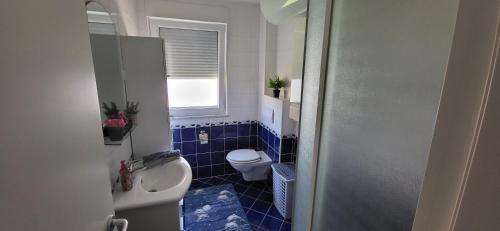 a blue tiled bathroom with a toilet and a window at Apartment Summer Dream in Punat