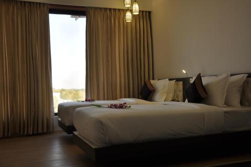 two beds in a hotel room with a window at Pride Biznotel Manjusar Vadodara Near Sokhda Lake in Vadodara