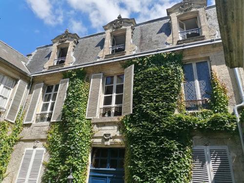 - un bâtiment recouvert de lierre avec des fenêtres et des portes dans l'établissement Jardin et Hotel Particulier, à Bayeux