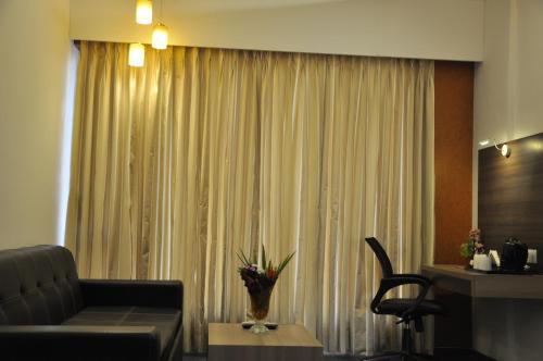 a living room with a couch and a vase of flowers at Pride Biznotel Manjusar Vadodara Near Sokhda Lake in Vadodara