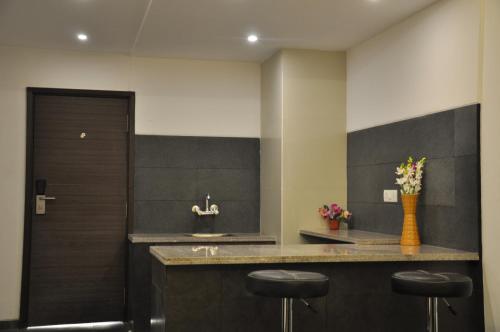 a kitchen with a sink and a counter with stools at Pride Biznotel Manjusar Vadodara Near Sokhda Lake in Vadodara