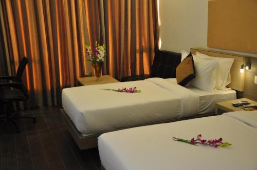two beds in a hotel room with flowers on them at Pride Biznotel Manjusar Vadodara Near Sokhda Lake in Vadodara