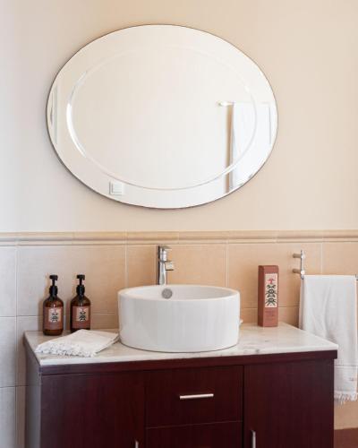 a bathroom with a sink and a large mirror at Aphaia Villa & Residences Aegina in Agia Marina Aegina