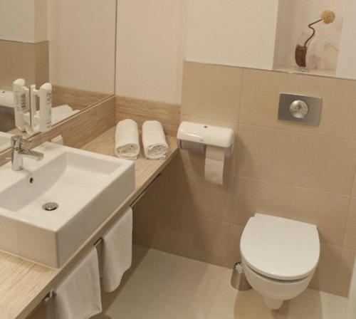 uma casa de banho com um WC branco e um lavatório. em Hotel Vis A Vis em Oleśnica