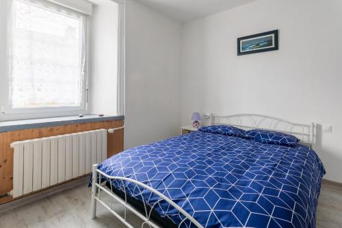 Cette chambre blanche dispose d'un lit bleu et d'une fenêtre. dans l'établissement Le gite de Kergrist, à Le Faouët