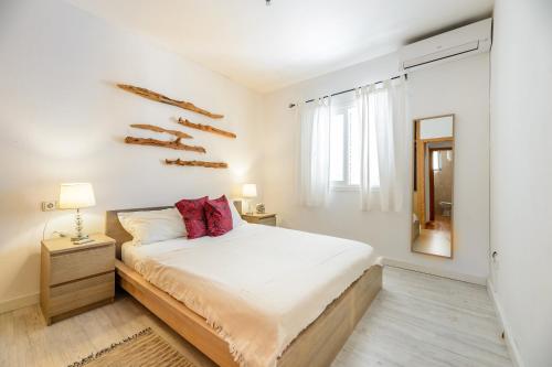 een witte slaapkamer met een bed en een spiegel bij Can Balafi in Cala Llonga