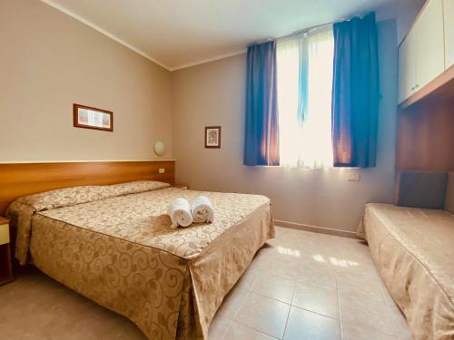 a bedroom with two beds and a window with blue curtains at Hotel Turandot in Torre del Lago Puccini