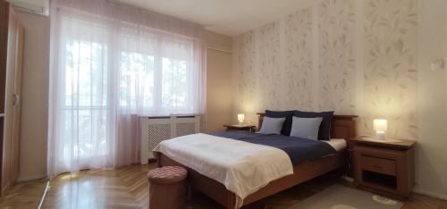 ein Schlafzimmer mit einem Bett und einem Fenster mit zwei Lampen in der Unterkunft Fürdő Apartman in Makó