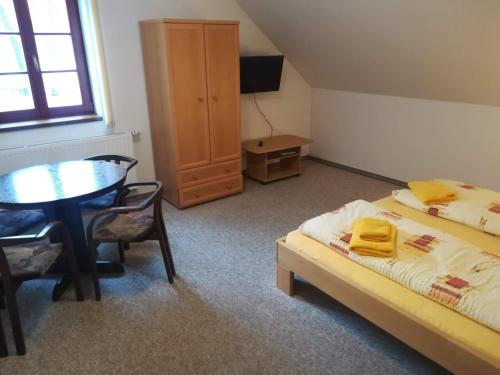 a bedroom with a bed and a table and a table and chair at apartmány Zak in Frymburk