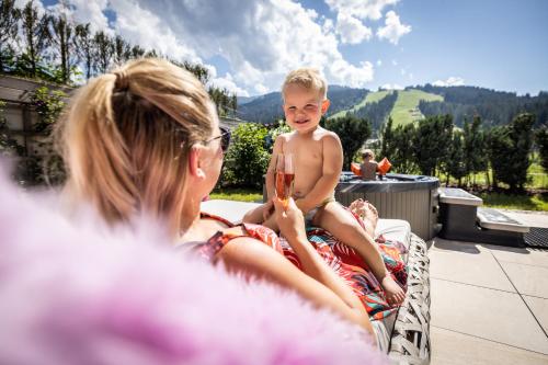 a woman and a child sitting in a chair with a glass of wine at Enjoy The Alps in Flachau