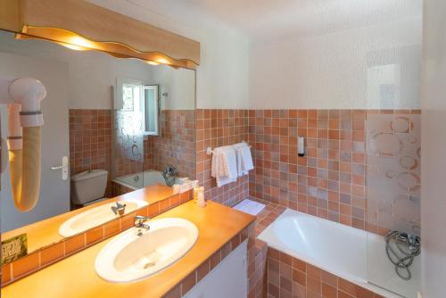 łazienka z 2 umywalkami, wanną i lustrem w obiekcie HOTEL LA QUIETUDE w mieście Les Issambres