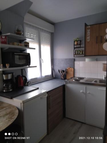 une petite cuisine avec un évier et un micro-ondes dans l'établissement Résidence l'hippocampe, à Mers-les-Bains