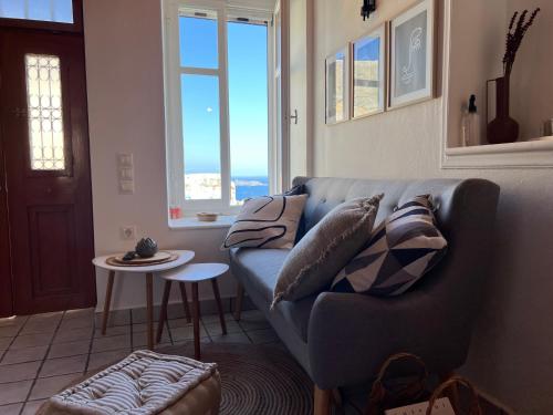 a living room with a blue couch and a window at Elia Concept Apartments in Ano Syros