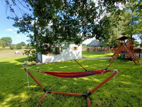 a hammock on the grass in front of a house at Smocze Ranczo 2 in Ośno Lubuskie