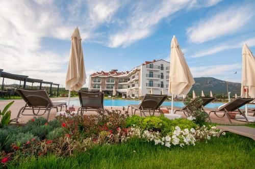 a group of chairs and umbrellas next to a pool at Acroter Hotel Spa - Alcohol Extra All Inclusive in Datca