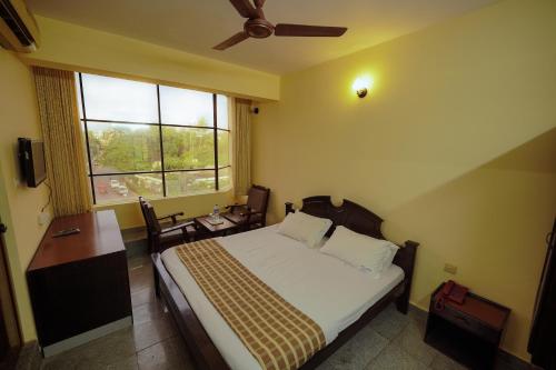 um quarto com uma cama, uma secretária e uma janela em Hotel oneiro em Thrissur