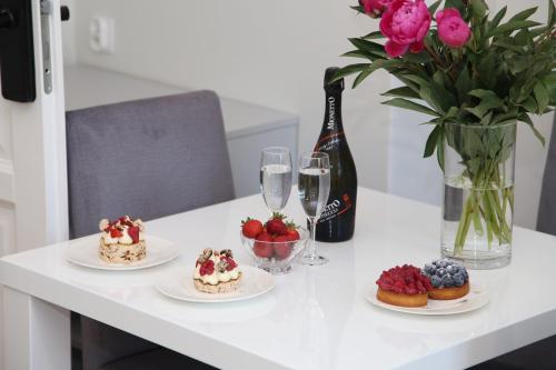 a table with plates of desserts and a bottle of wine at Apartamenty al Mare Sopot in Sopot