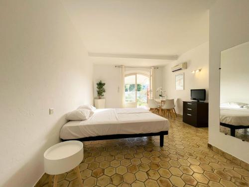 une chambre avec un lit, un bureau et une télévision dans l'établissement Studio 2 - LES SUITES DE ROBINSON - Résidence avec piscine en bord de Siagne, à Mandelieu-La-Napoule, à Mandelieu-la-Napoule