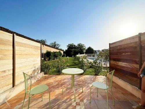 eine Terrasse mit einem Tisch, Stühlen und einem Zaun in der Unterkunft Studio 2 - LES SUITES DE ROBINSON - Résidence avec piscine en bord de Siagne, à Mandelieu-La-Napoule in Mandelieu-la-Napoule