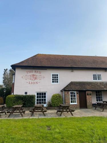 un edificio con mesas de picnic delante de él en Red Lion, en Winfrith Newburgh