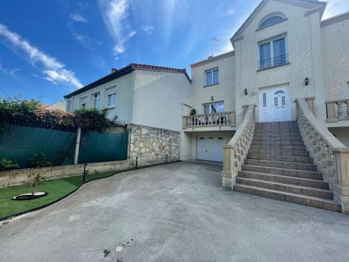 a large white house with a driveway and stairs at Proche Paris et Disney Maison 90 M2 CLIMATISÉ bord de Marne in Gournay-sur-Marne