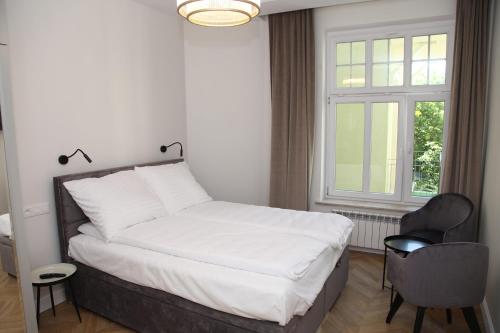 a bedroom with a bed and a chair and a window at Apartamenty al Mare Sopot in Sopot