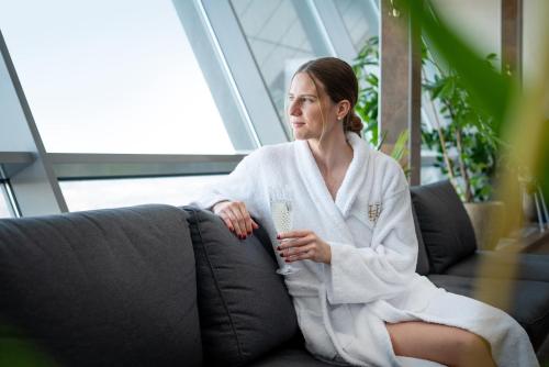 Eine Frau, die mit einem Glas Wein auf einer Couch sitzt. in der Unterkunft Hotell Hallstaberget in Sollefteå