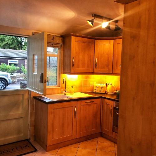 a kitchen with wooden cabinets and a sink at The Rose Cottage in Wisborough Green