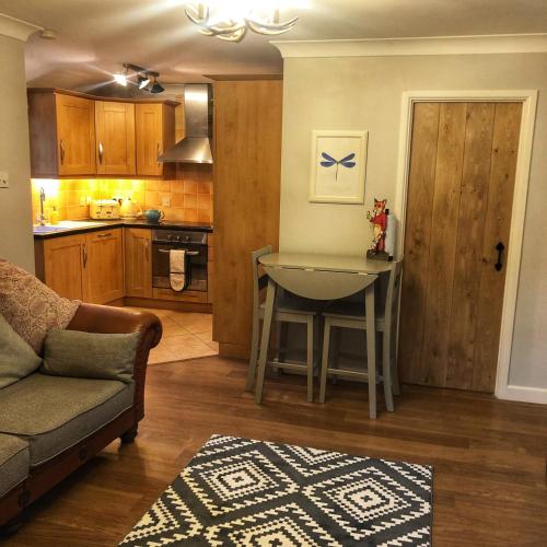 a living room with a table and a kitchen at The Rose Cottage in Wisborough Green