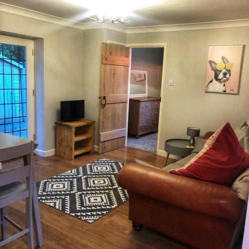 a living room with a couch and a television at The Rose Cottage in Wisborough Green