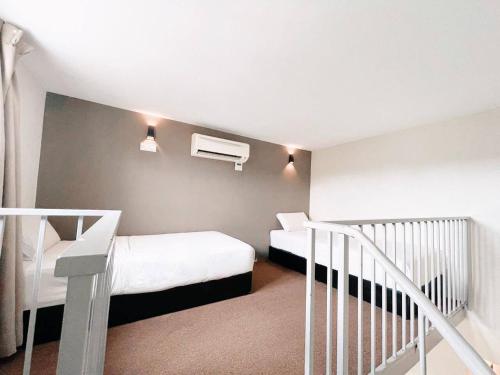 a small bedroom with two beds and a staircase at KARANG TIMUR MOTEL in Kuantan