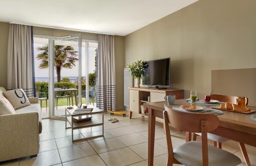 a living room with a table and a television at Résidence Pierre & Vacances Premium Le Coteau et la Mer in Tréboul