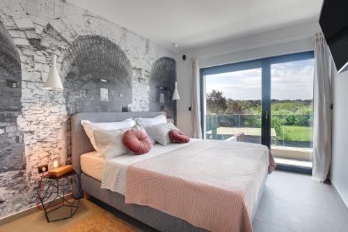 sypialnia z kamienną ścianą i łóżkiem z poduszkami w obiekcie Villa Monte Grosso 2 w Puli